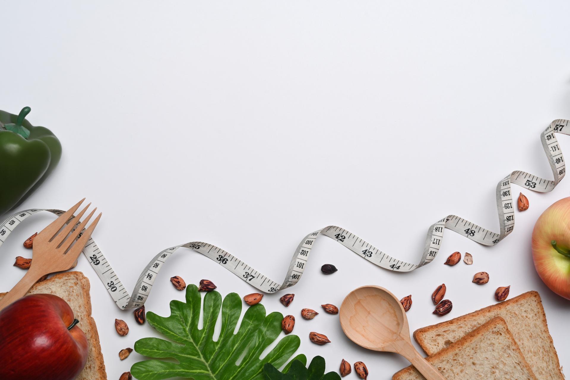 Flat lay, measuring tape and healthy food on white background with copy space for text. Healthy lifestyle concept.